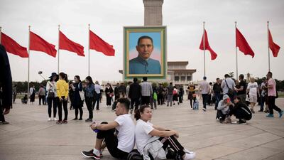 A couple sit back-to-back past a portrait of nationalist leader Sun Yat-sen in Tiananmen Square, Beijing. Nicolas Asfouri / AFP Photo