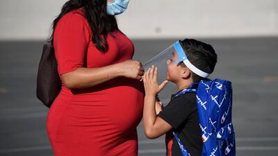 A parent adjusts her son's visor on the first day of school at Enrique Camarena Elementary School in Chula Vista, California, on July 21, 2021. AP