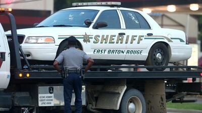 A police officer stands in front of an East Baton Rouge police car with bullet holes as it is towed away from the scene where three police officers were killed Sunday morning. Sean Gardner / Getty Images / AFP