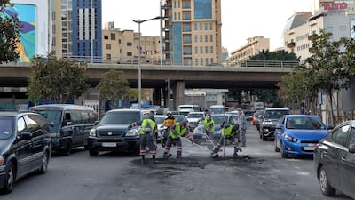 People clean up a street after a night of clashes between supporters of Hezbollah and Amal and security forces. EPA