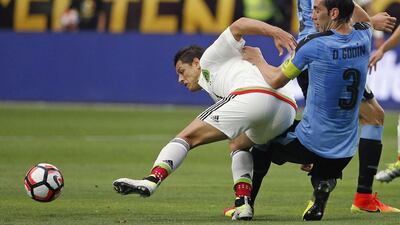 Mexico’s Javier Hernandez, left, tries to keep the ball away from Uruguay’s Diego Godin. Ross D. Franklin / AP Photo