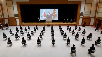 New employees of Japan's defence ministry sit on chairs spaced apart for social distancing as they watch a video message of Defence Minister Taro Kono during a ceremony in Tokyo. AFP