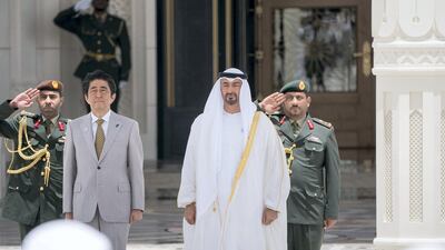 Sheikh Mohammed bin Zayed,, Crown Prince of Abu Dhabi and Deputy Supreme Commander of the UAE Armed Forces (right), and Shinzo Abe, Prime Minister of Japan (left), stand for the national anthem during a reception at the Presidential Palace. Rashed Al Mansoori / Crown Prince Court - Abu Dhabi