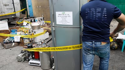 A member of the Philippine Drug Enforcement Agency (PDEA) puts caution tape around seized equipment for the manufacture of illegal drugs in Valenzuela City, north of Manila, Philippines, on October 12, 2017. Rolex Dela Pena / EPA