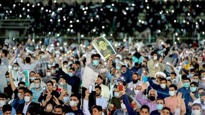 In this Wednesday, June 9, 2021 photo, a supporter of the presidential candidate Ebrahim Raisi, currently judiciary chief, hold his posters during a campaign rally at the Takhti Stadium in Ahvaz, Iran. Around 5,000 of people have gathered in a football stadium in southeastern city of Ahvaz to support the Iranian hard-line presidential candidate, Iranian media reported. (Alireza Mohammadi/ISNA via AP)