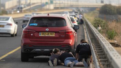 People take cover on the main highway as siren warnings for rockets are heard in Kfar Saba, Israel. Getty Images