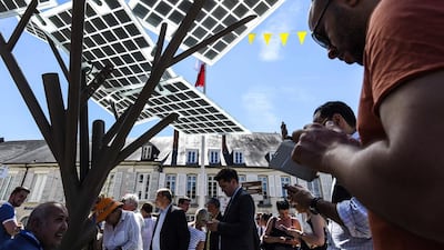 People connect their smart-phones to the first "eTree" provided in Europe. Via its photovoltaic foliage, users can recharge cell phones, surf the internet or recharge an electric bike. The tree also distributes fresh water and lights up at night. Philippe Desmazes / AFP