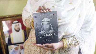 Aisha, the niece of UAE's first martyr Salem Suhail bin Khamis Al Dahmani, holds a biography publication about her martyred uncle. Reem Mohammed / The National