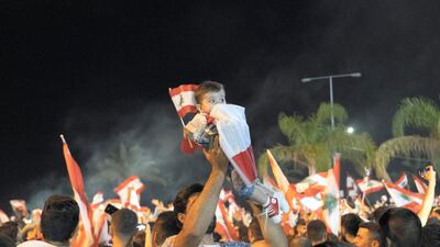 A man holds a baby wrapped in the Lebanese flag high in the air during a protest in Sour. William Lowry / The National