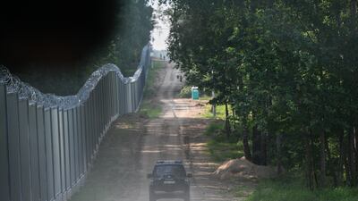A Polish border guard patrol car rides along the metal border wall in Kuznica. Getty Images