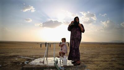A women and a girl wash at a tap at a temporary displacement camp set up next to a Kurdish checkpoint on in Kalak, Iraq. Dan Kitwood / Getty