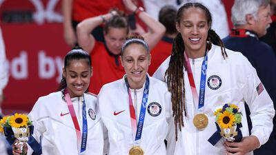 Brittney Griner with teammates Diana Taurasi and Skylar Diggins posing for pictures with their gold medals on the podium during the medal ceremony for the women's basketball competition of the Tokyo 2020 Olympic Games. AFP
