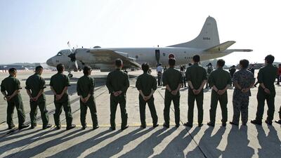 Ground crew members stand in front of a Japan Maritime Self-Defense Force P3C patrol plane before it leaves the Royal Malaysian Air Force base for Australia to join a search and rescue operation for the missing Malaysia Airlines, flight MH370, in Subang, Malaysia. Lai Seng Sin / AP