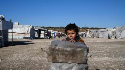 A displaced Syrian boy stands next to bags of aid at a camp for the internally displaced near Dayr Ballut, near the Turkish border in the rebel-held part of Aleppo province. AFP