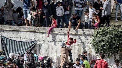 Newly arrived migrants and refugees jump from a wall down into the Istanbul’s Esenler Bus Terminal as they wait for buses going to the Turkish-Greek border. Ozan Kose / AFP Photo