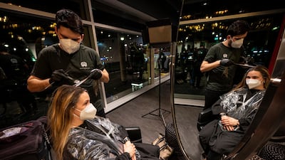 The first customer of Shan Rahimkhan's barbershop gets her hair cut and colored after the reopening in Berlin. AP Photo