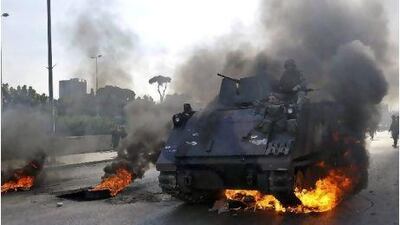 A tank passes burning tyres in Beirut. Tanks are stationed in politically sensitive areas in the Lebanese capital.