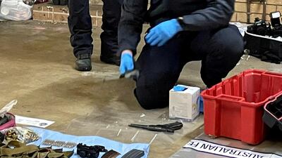 Forensics officers examine weapons from a cache seized by Australian Federal Police during Operation Ironside on Tuesday. Reuters