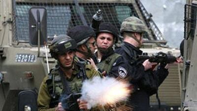 An Israeli soldier fires tear gas at Palestinian stone-throwers during clashes over the last two days in Hebron, West Bank.