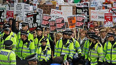 Police officers walk in front of students from across the UK marching during an anti-cuts protest in London on November 9. The public-sector strike promises to have much more impact on the country.