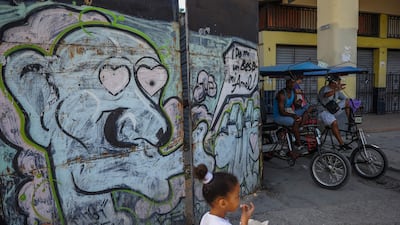 Rickshaws are parked near a graffiti of street art in Havana, on July 12, 2017. / AFP PHOTO / YAMIL LAGE