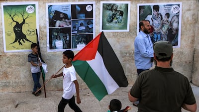 A boy walks with a Palestinian flag at a make-shift exhibition marking the 11th anniversary of chemical attacks in Eastern Ghouta near Damascus, in Syria's rebel-held northern city of Idlib. AFP