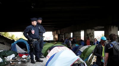 French CRS police watch a group of migrants near their tents as police evacuate hundreds of migrants living in makeshift camps in Paris, France. Benoit Tessier / Reuters