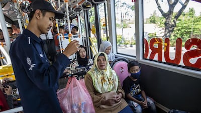 A bus conductor collects used plastic bottles as fare payment on board a Suroboyo bus in the Indonesian city of Surabaya. All photos by AFP
