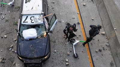 Two Californai Highway Patrol officers try to dodge rocks being thrown near the metropolitan detention center. AP