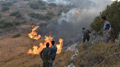 A handout picture released by the official Syrian Arab News Agency (SANA) shows security forces walking on a burnt hill Ain Halaqim, in the western countryside of Hama Governorate, during fires. AFP