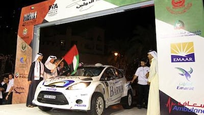 Sheikh Mansour bin Mohammed, left, and Mohammed ben Sulayem, the former UAE rally driver, second left,drop the flag for Nasser Al Attiyah at the ceremonial start of the Dubai International Rally Thursday night.