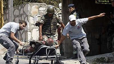 Rescue workers in Adaisseh evacuate a Lebanese soldier wounded in a clash with Israeli troops yesterday. The violence left two Lebanese soldiers, an Israeli officer and one civilian dead.