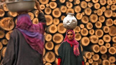 A woman walks home carrying a metal pitcher filled with drinking water on in the outskirts of Srinagar. Danish Ismail / Reuters