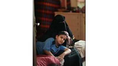 Layla Ali Hassan with her son Hamdan Mustafa, eight, in their apartment in Ajman. Mrs Hassan's husband left his family and she divorced him. He has since disappeared and she struggles to provide for her children.