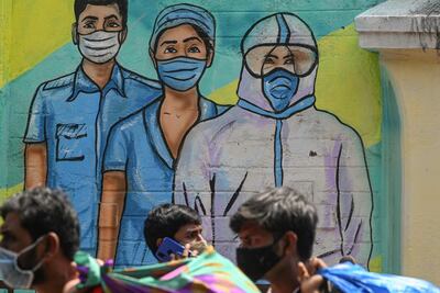 Pedestrians walk past a mural depicting medical staff as frontline Covid-19 warriors, in Mumbai. AFP