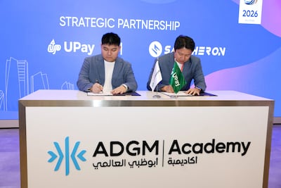 Owen Yang, founder and chief executive of UPay, signs the agreement with Jag Foo, chief security and policy officer at Safeheron. Chris Whiteoak / The National