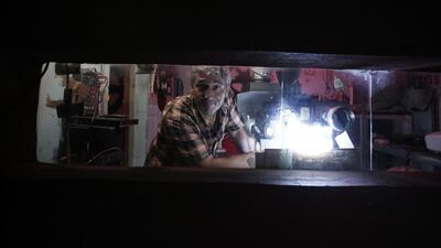 Pavlos Lepeniotis operates his equipment and peers out from the projection booth at the Zefyros vintage-movie cinema in Petralona, near central Athens.