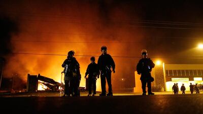Police in riot gear stand in front of a burning building in Ferguson, Missouri. Larry W. Smith / EPA
