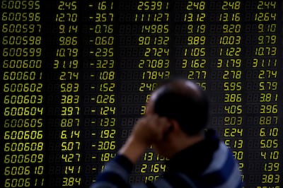 An investor sits in front of an electronic board displaying stock prices at a brokerage house in Beijing. AP Photo