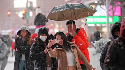 People pose for photos as snow falls in Times Square. Reuters