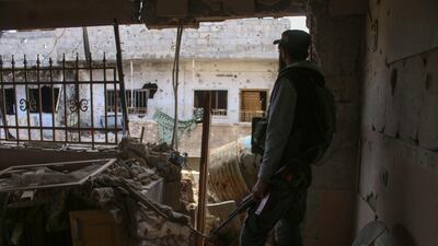 An opposition fighter looks out from a destroyed building in a rebel-held area in the southern Syrian city of Daraa on April 22, 2018. After the capture of Eastern Ghouta the Syrian president now has forces ready to redeploy elsewhere in the war-ravaged country. Mohamad Abazeed / AFP / April 22, 2018