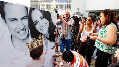 Fans and tourists sign a giant card congratulating Britain's Prince William and Kate, Duchess of Cambridge, on the birth of their baby boy. AP Photo / Nick Ut
