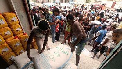 Workers unload sacks of wheat flour as people gather outside an aid distribution centre in the Red Sea port city of Al Hodeidah, Yemen on June 14, 2018. Abduljabbar Zeyad / Reuters