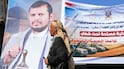 A Houthi fight walks past a poster of the group's leader, Abdul-Malik Al Houthi. AFP
