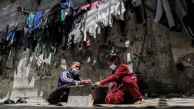 Children study outside their home in Rafah camp for Palestinian refugees in the southern Gaza Strip on April 6, 2021, amidst a lockdown due to the COVID-19 coronavirus pandemic. / AFP / SAID KHATIB