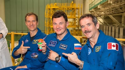 At the Baikonur Cosmodrome in Kazakhstan in December 2012, Expedition 34/35 Soyuz Commander Roman Romanenko (centre) holds a toy 'talisman' that his nine-year old daughter, Anastasia, gave him to hang over his seat. He is pictured with Flight Engineer Tom Marshburn of NASA (left) and Flight Engineer Chris Hadfield of the Canadian Space Agency. Victor Zelentsov / Nasa