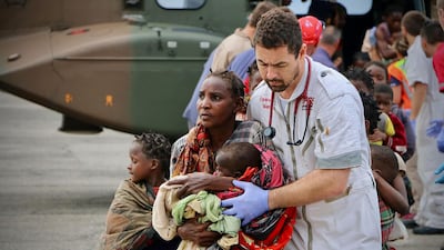 People are escorted to safety by aid workers at the airport of the coastal city of Beira in central Mozambique. AFP