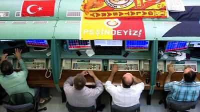 Flags decorate the working areas of traders as they monitor financial information on the floor of the Borsa Istanbul, the stock exchange in Istanbul. A bank on shorting seven domestic banks last month initially pushed up their shares, helped by a broader market gain, but volumes slumped before later recovering. Bloomberg