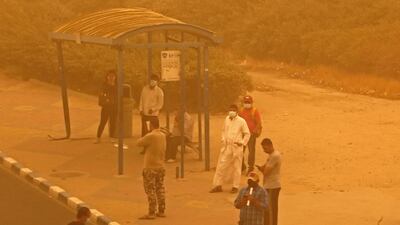 Pedestrians wait for a bus in Kuwait City. Kuwait's Ministry of Interior urged the public to exercise caution as the dust severely reduced visibility. AFP