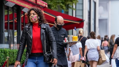 A waiter wearing a face mask serves customers on Champs Elysees, in Paris. France warned its citizens against travelling to Spain and Portugal because of a surge in Covid cases caused by the Delta variant. .